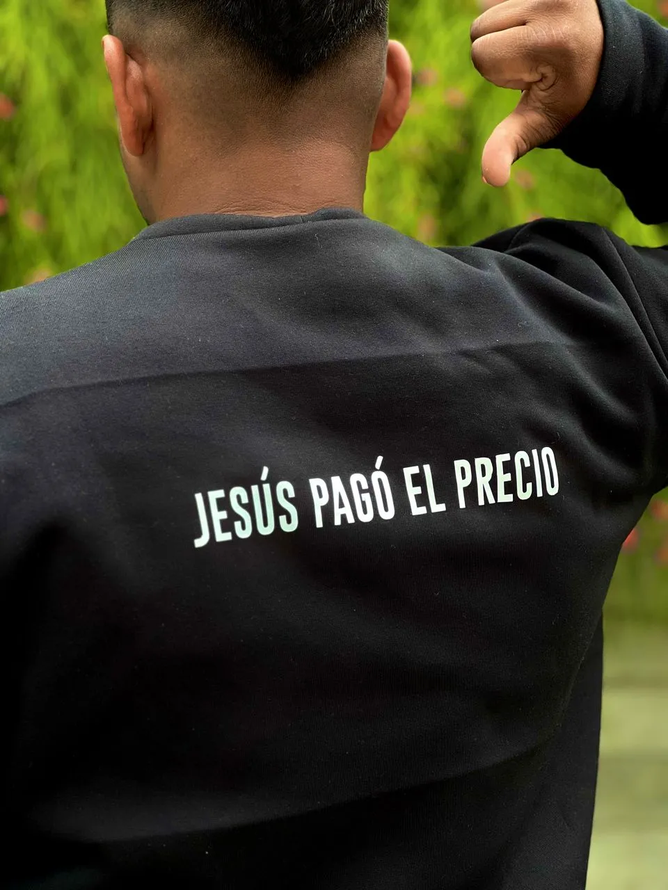 Suéter negro con texto en la espalda que dice Jesús pagó el precio en letras blancas.