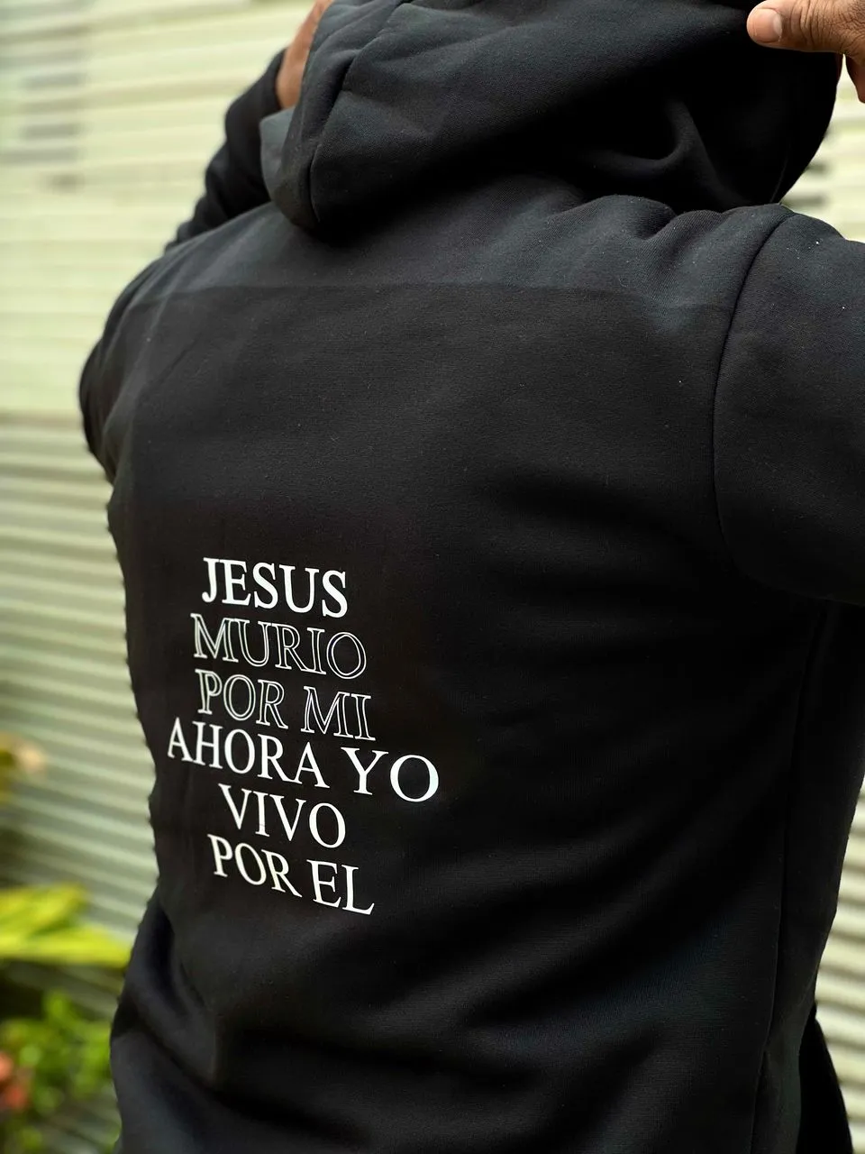 Suéter negro con texto en la espalda que dice Jesús murió por mí, ahora yo vivo por Él en letras blancas.