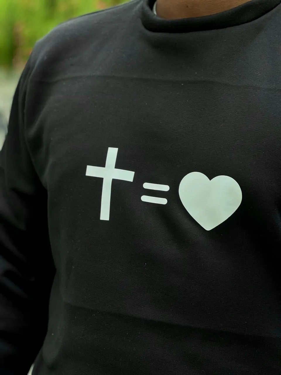 Suéter negro con imagen que combina una cruz y un corazón en diseño simple y llamativo.
